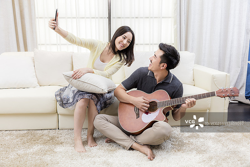 年轻的夫妻在客厅弹吉他图片素材