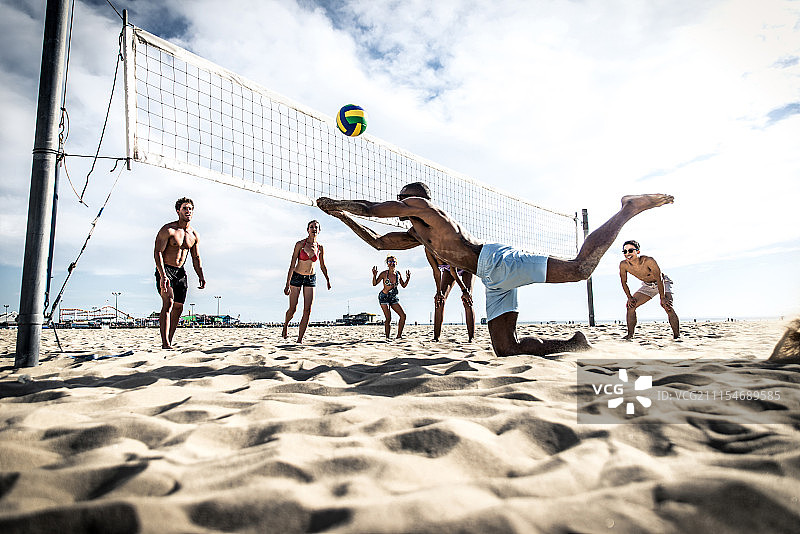 一群朋友在沙滩上玩沙滩排球。图片素材