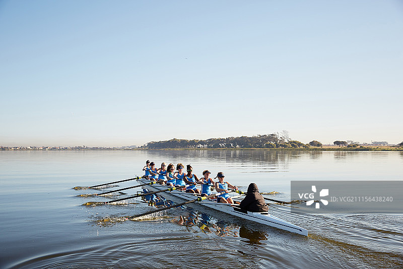 女子赛艇队在宁静的湖面上划桨图片素材