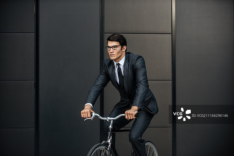 英俊的年轻商人，骑着现代自行车。图片素材