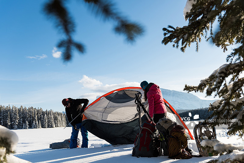 一对夫妇在雪景中搭帐篷图片素材