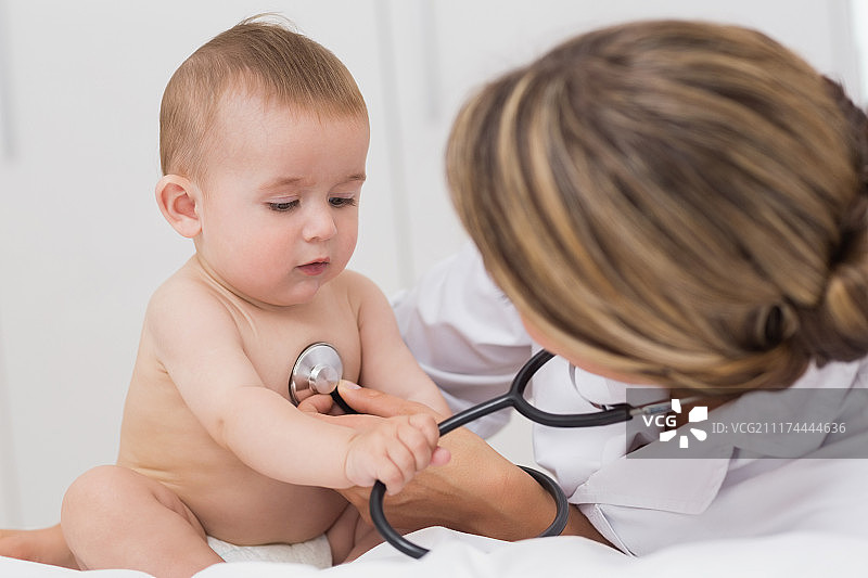 医生检查时，婴儿玩听诊器图片素材