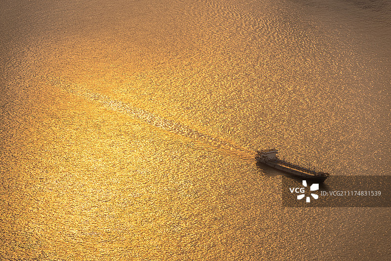 行驶在阳光照射的江面上的船只图片素材