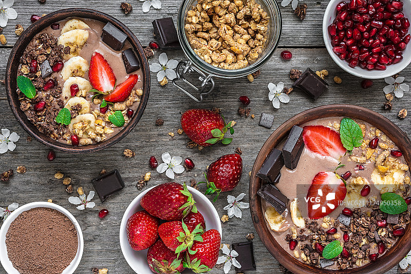 巧克力香蕉蛋白冰沙碗与格兰诺拉，草莓，石榴和巧克力棒图片素材