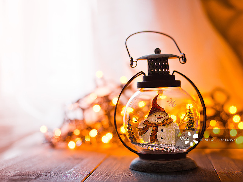 玻璃灯笼与燃烧的蜡烛，圣诞礼物和一个发光的花环在木桌子上图片素材
