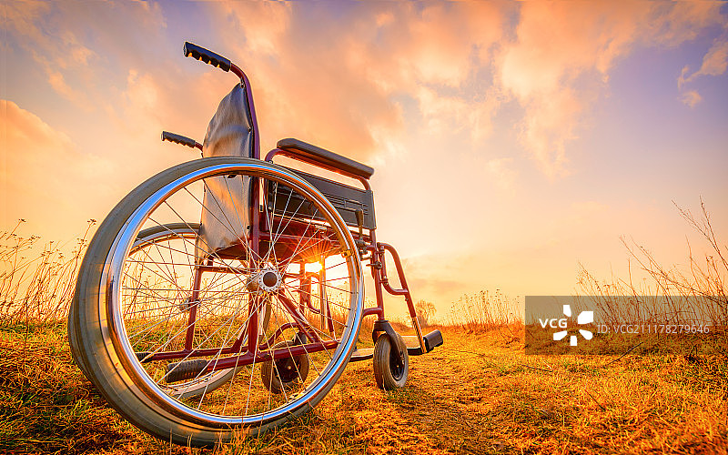日落时草地上的空轮椅。奇迹的概念。图片素材