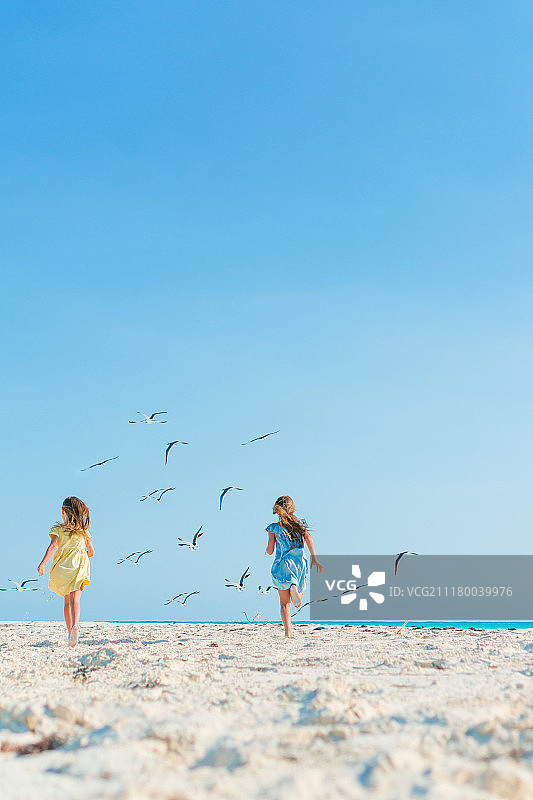 小女孩在热带海滩上玩得很开心，在海边一起玩图片素材