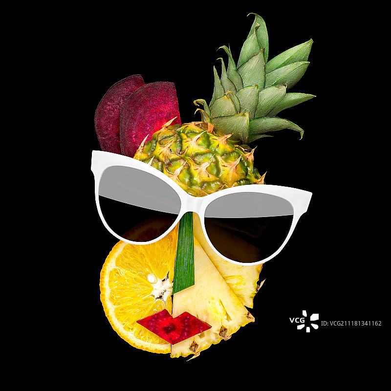 美味的艺术. .这是一张立体主义风格的女性脸戴着水果和蔬菜制成的太阳镜的创意照片，背景是黑色的。图片素材