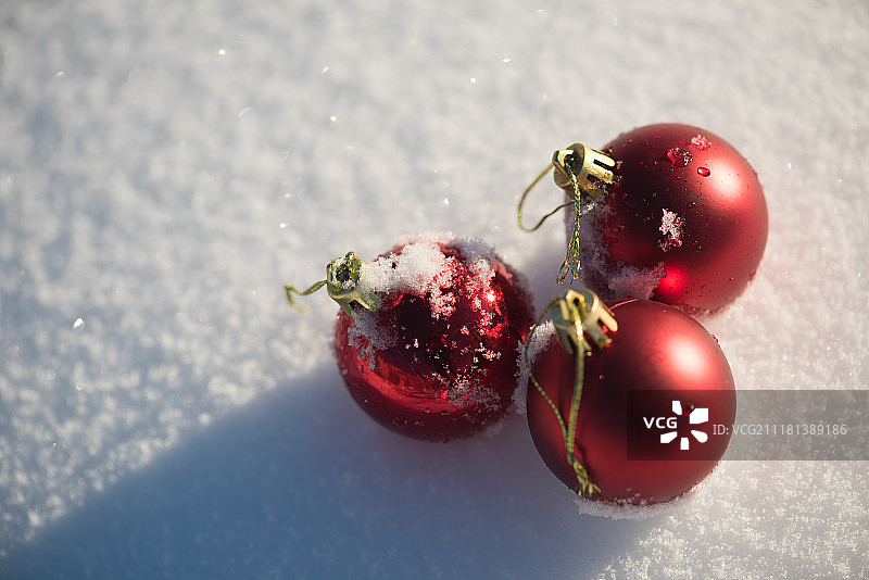 圣诞红球装饰在新鲜的雪背景在美丽的阳光明媚的冬日图片素材