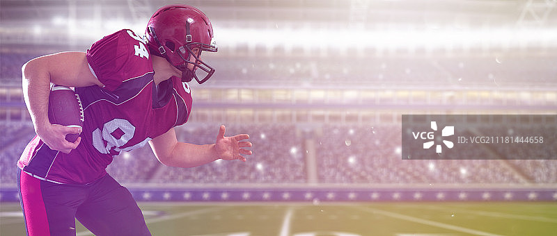 美国橄榄球运动员带着球在有灯光和信号弹的大型现代运动场上奔跑图片素材