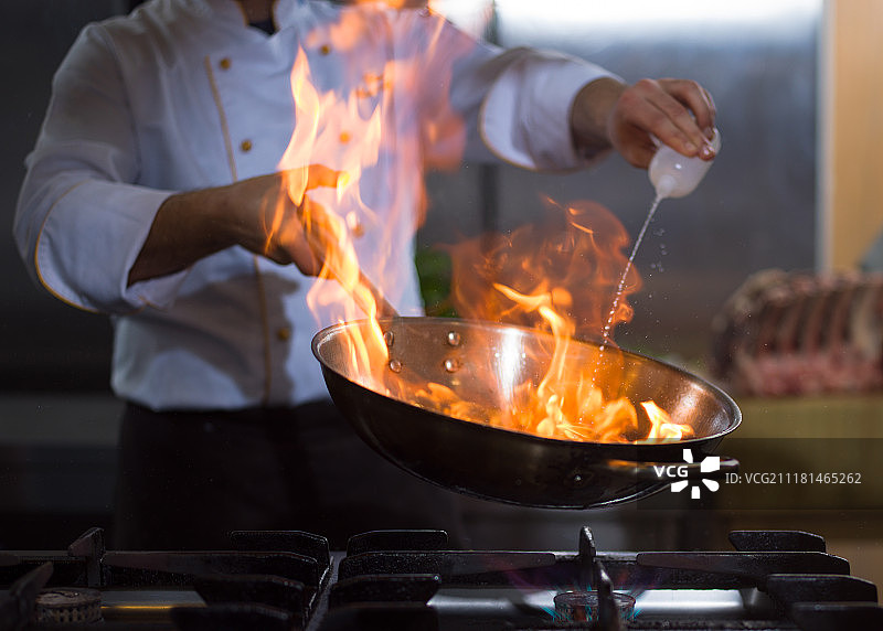 厨师长在餐厅厨房烹饪和做火苗。厨师在做食物上的火焰图片素材