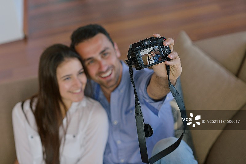 快乐的年轻夫妇在家里玩数码相机图片素材