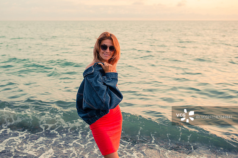 户外时尚肖像时尚女孩戴着时髦的太阳镜和牛仔裤夹克在海滩上图片素材