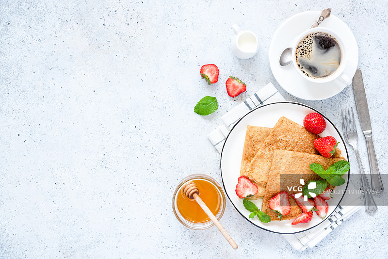 法式可丽饼或俄罗斯布里尼配新鲜草莓，蜂蜜，咖啡图片素材