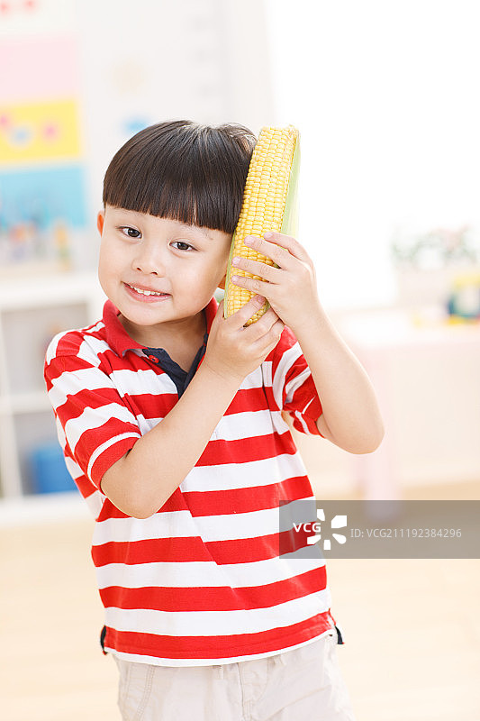 可爱的小男孩头手拿玉米图片素材