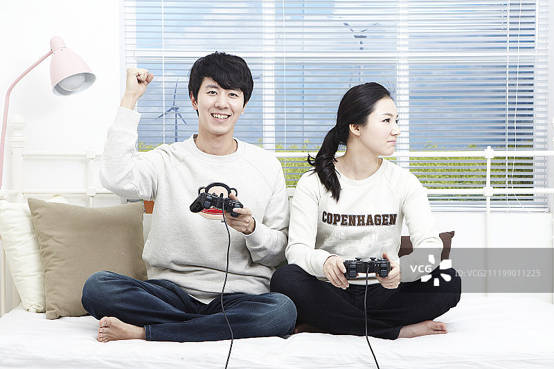 新婚夫妇坐在沙发上玩游戏机图片素材