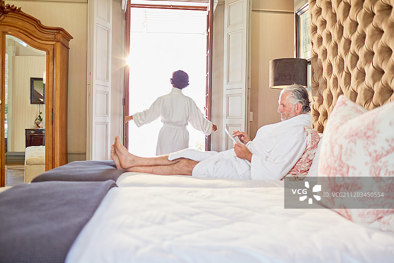 一对穿着浴袍的成熟夫妇在酒店的卧室里放松图片素材