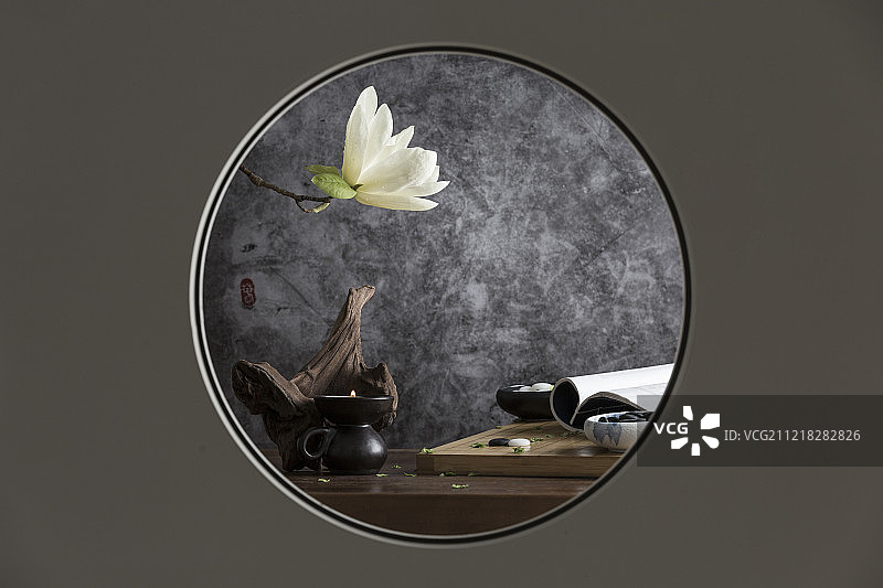 中式圆窗透景创意-围棋、烛台和玉兰花静物图片素材