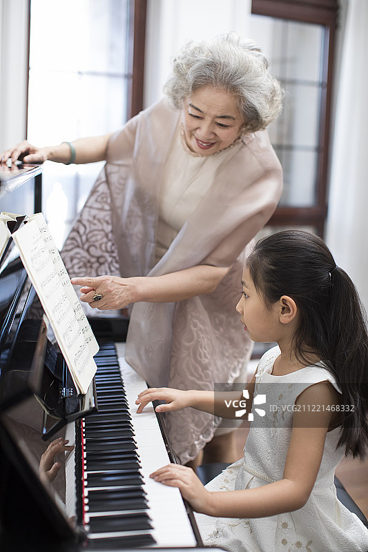 奶奶教女孩弹钢琴图片素材