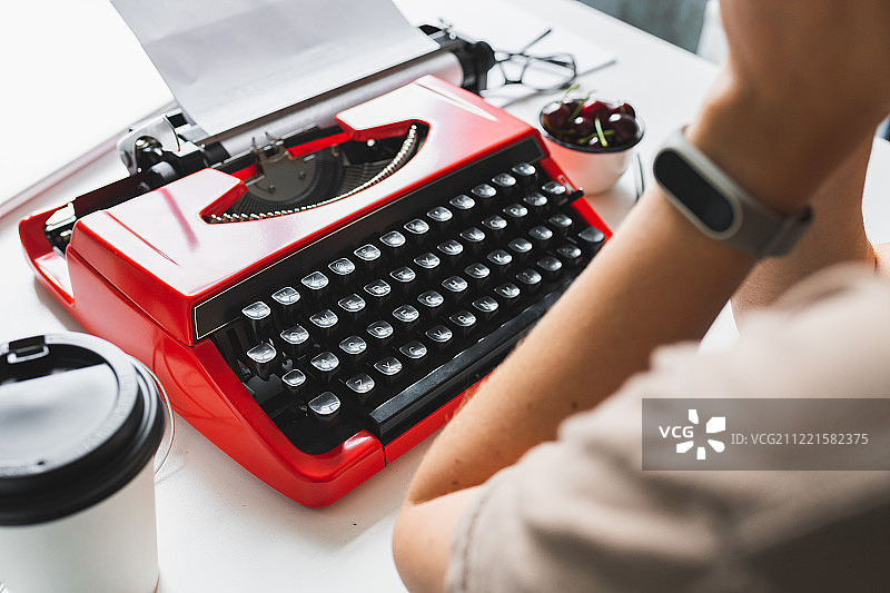 一位女作家在她的书桌上用红色打字机思考着写一本书图片素材