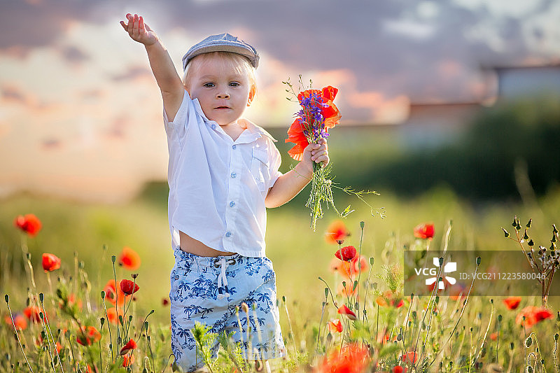 快乐美丽的蹒跚学步的孩子，捧着一束野花图片素材