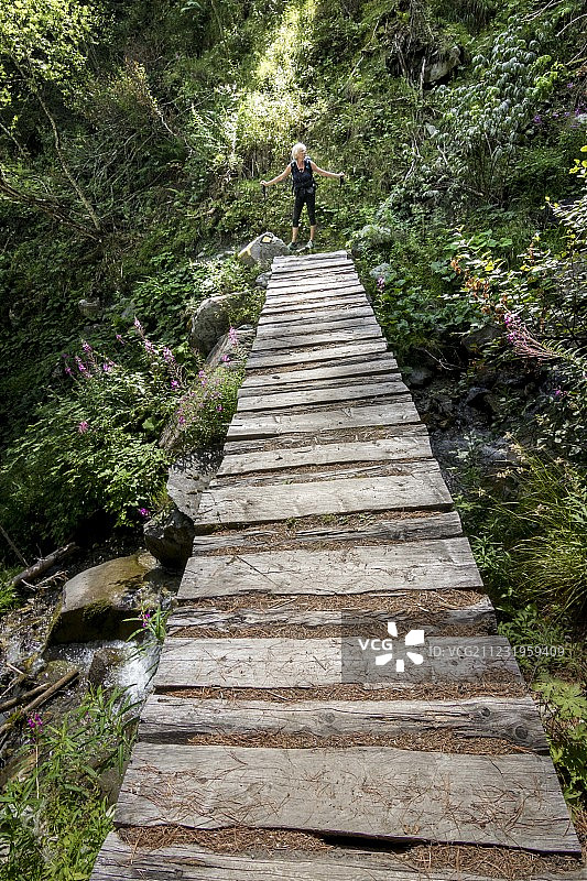 远眺高级女子徒步旅行onÂ footpathÂ在森林，Â HauteÂ路线，Â ValaisÂ广州，瑞士图片素材