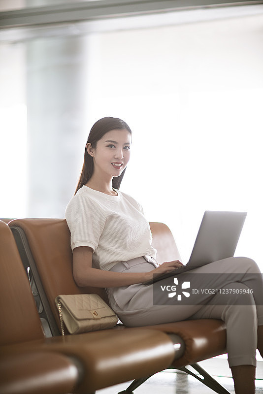 年轻女子在机场候机室使用笔记本电脑图片素材