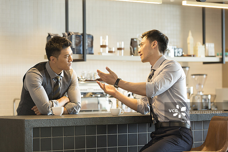 两个成功商务青年男子在酒店咖啡馆吧台喝咖啡沟通讨论工作图片素材