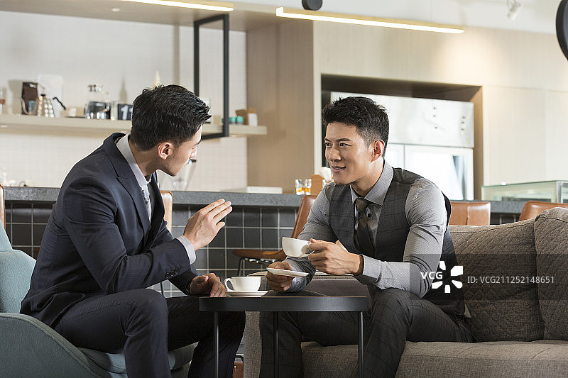 两个成功商务青年男子在酒店咖啡馆喝咖啡沟通讨论工作图片素材