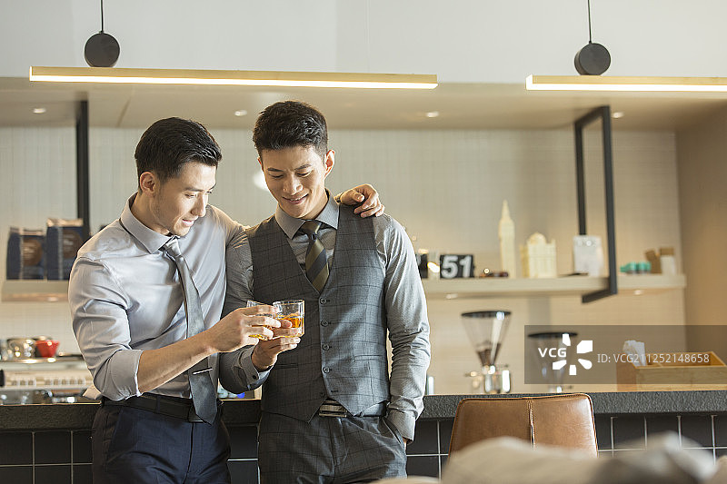 两个成功商务青年男子拿着酒杯干杯庆祝成功图片素材