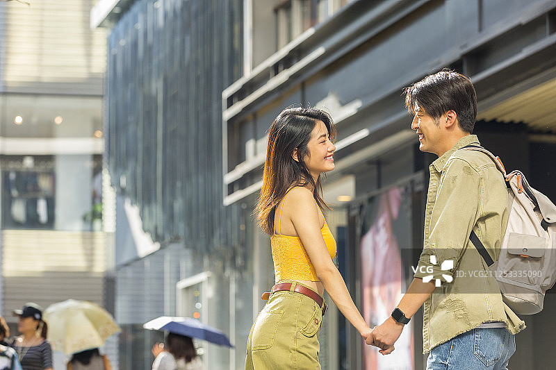 甜蜜情侣在户外商业街手牵手浪漫逛街旅行图片素材