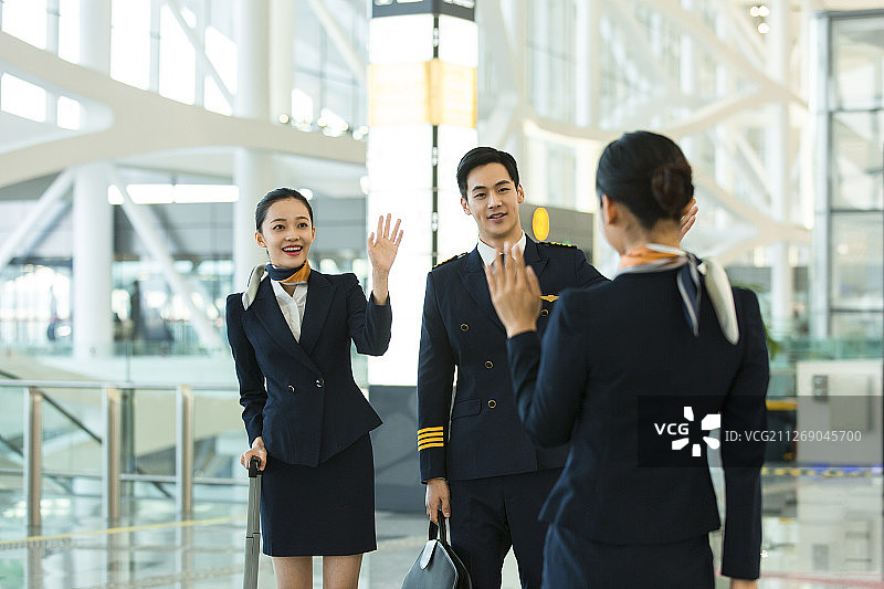飞机机长和两名空姐在机场见面招手打招呼图片素材