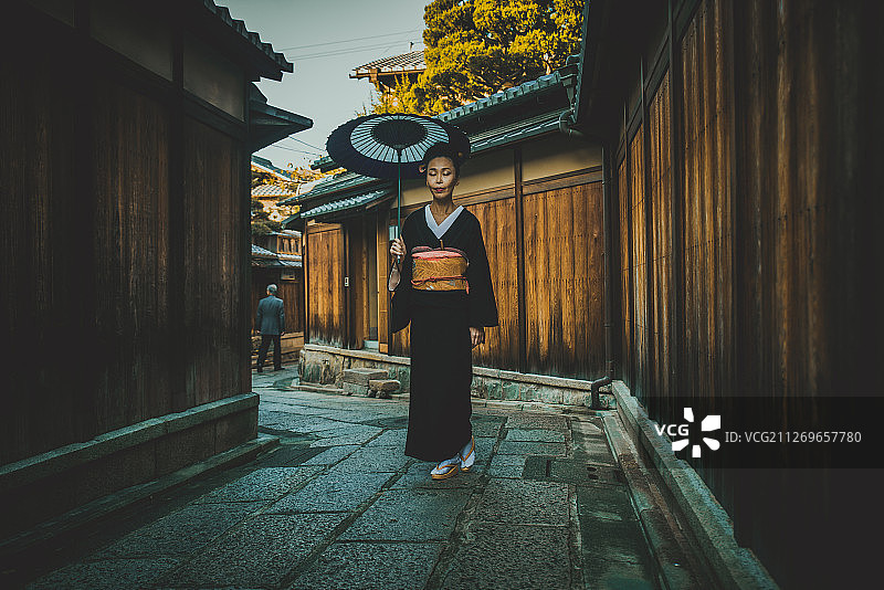 日本京都，带着伞行走的日本老年妇女图片素材