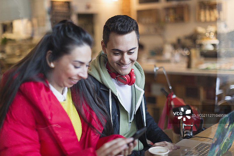 年轻夫妇在咖啡馆使用智能手机和笔记本电脑图片素材