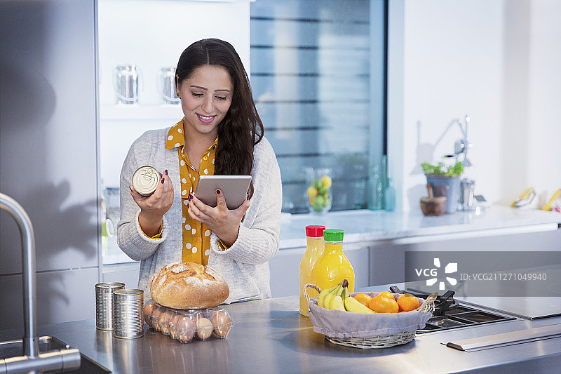 女人在厨房用电子平板检查食物标签图片素材