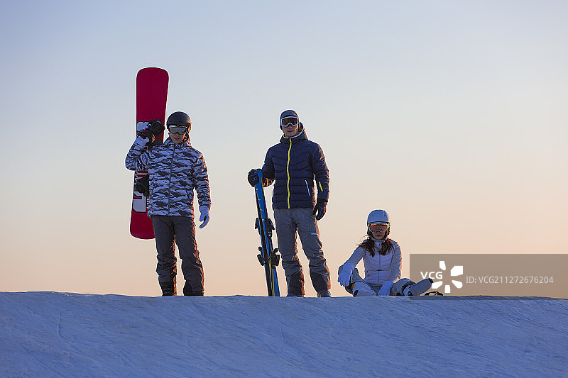 三个青年男女拿着滑雪板在户外滑雪场休息图片素材