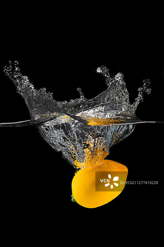 黄色柠檬落入水中凝固水花的瞬间图片素材