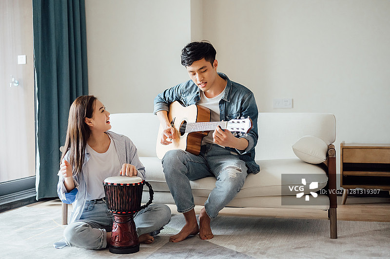 亚洲年轻情侣在家弹琴唱歌图片素材