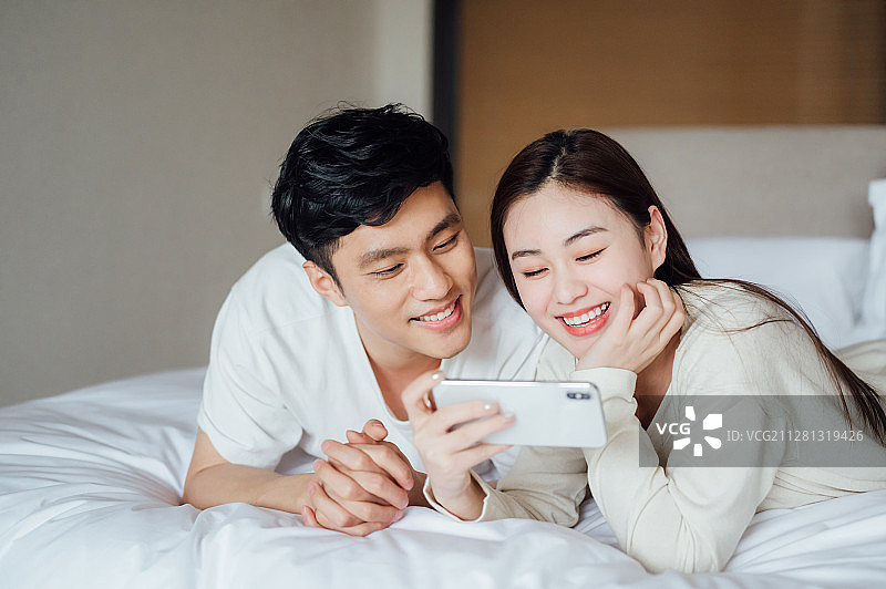 亚洲年轻情侣在家使用智能手机图片素材