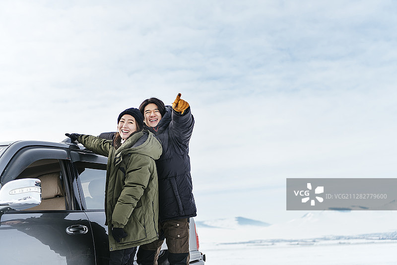 这是一对情侣站在雪地上抱着车顶的照片图片素材