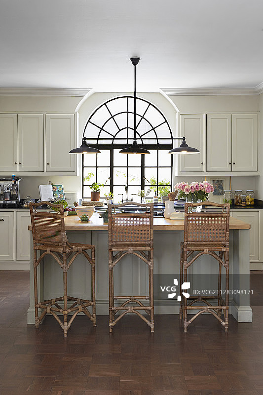 厨房里有黑色的金属拱形窗户和藤条靠背的高脚凳图片素材