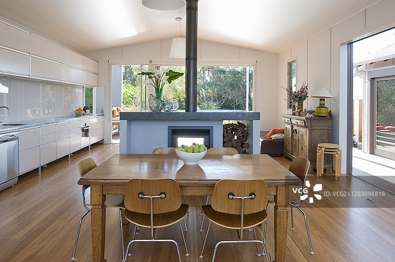 餐桌，椅子和壁炉旁边的白色厨房柜台在开放式的室内图片素材