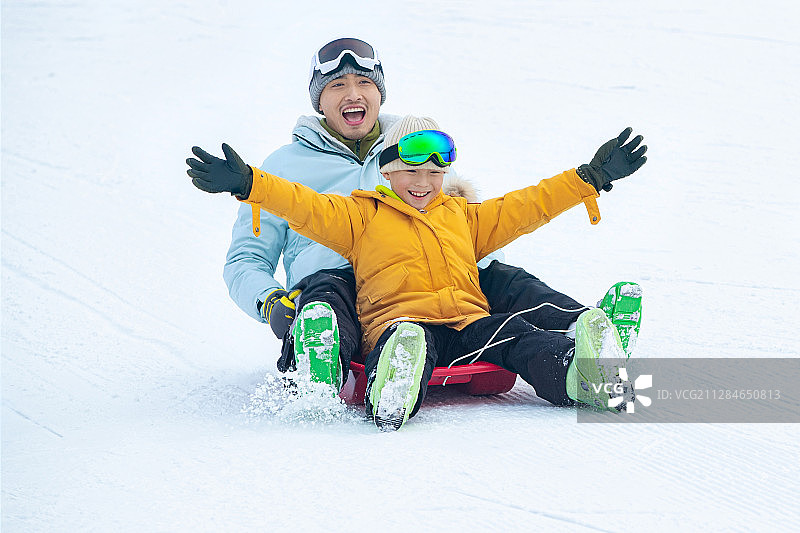 快乐父子坐着雪上滑板滑雪图片素材