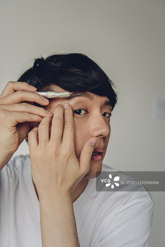 男人用剃刀对着镜子剃眉毛的照片图片素材