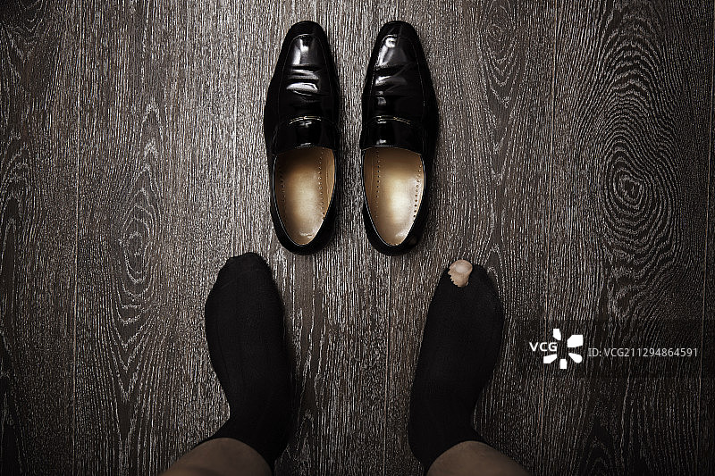 一个穿着破袜子站在鞋子旁边的人的脚图片素材
