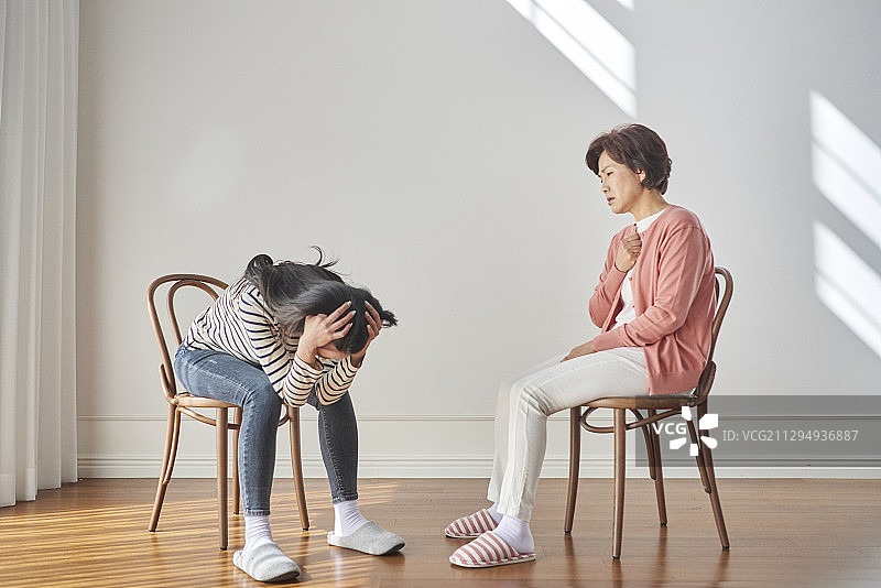 母亲和女儿面对面坐在椅子上发生冲突图片素材