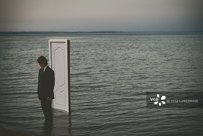 一个人站在门口的海里。超现实的上下文。非常适合书的封面图片素材