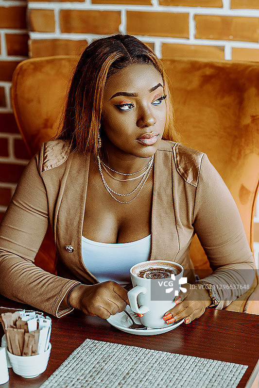 年轻黑人妇女坐在咖啡馆里看向别处，加纳，阿克拉图片素材