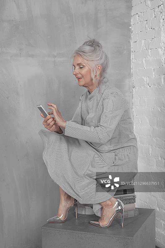 头发花白、穿着考究的老年女性在使用手机图片素材