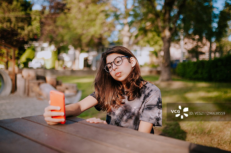 在加拿大维多利亚的公园里，一个小女孩用智能手机自拍图片素材